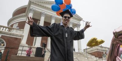 Student in front of the Rotunda in graduation robes
