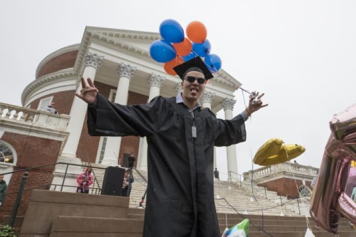 Student in front of the Rotunda in graduation robes